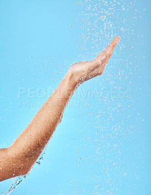 Buy stock photo Hand, shower and water for skincare hygiene, wash or dermatology against a blue studio background. Arm and hands of person in healthy wellness, skin hydration and washing for body care treatment