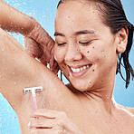 Shower, woman shave armpit with razor and clean beauty with water and hygiene for grooming against blue studio background. Happy Asian model, healthy skin and wet with hair removal and shaving.