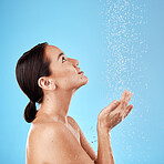 Water, shower and woman washing in a studio for body care, hygiene and to stop germs or bacteria. Health, wellness and Asian model cleaning her skin with aqua while isolated by a blue background.