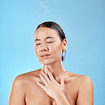 Shower, water and cleaning with a model woman washing her face or body in studio on a blue background. Skincare, wellness and wet with an attractive young female washing her skin in the bathroom