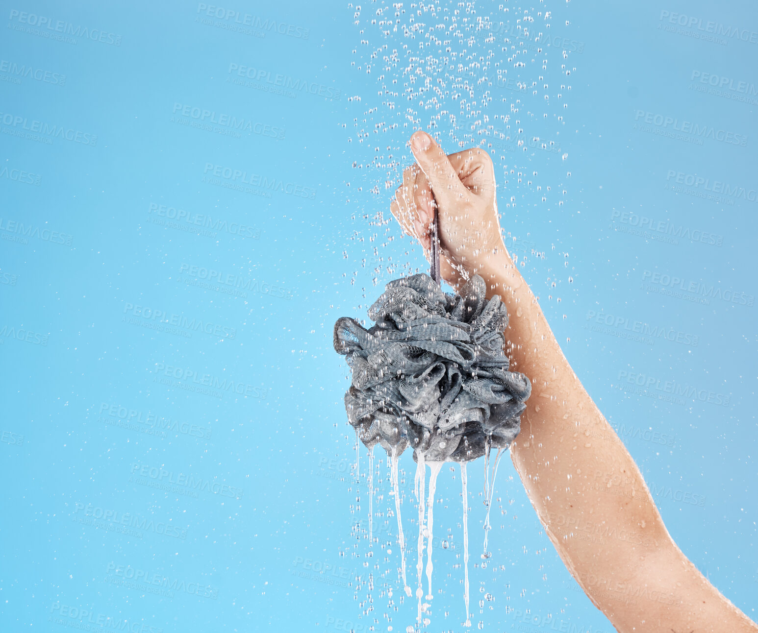 Buy stock photo Shower, loofah and hand of woman in studio on blue background mock up. Skincare, water splash and female model holding sponge for showering, washing or bathing for hygiene, health or wellness mockup
