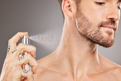 Buy stock photo Hand, perfume and beauty with a man model spraying cologne in studio on a gray background for fresh scent. Product, luxury and spray with a handsome young male inside to apply an aroma for smell