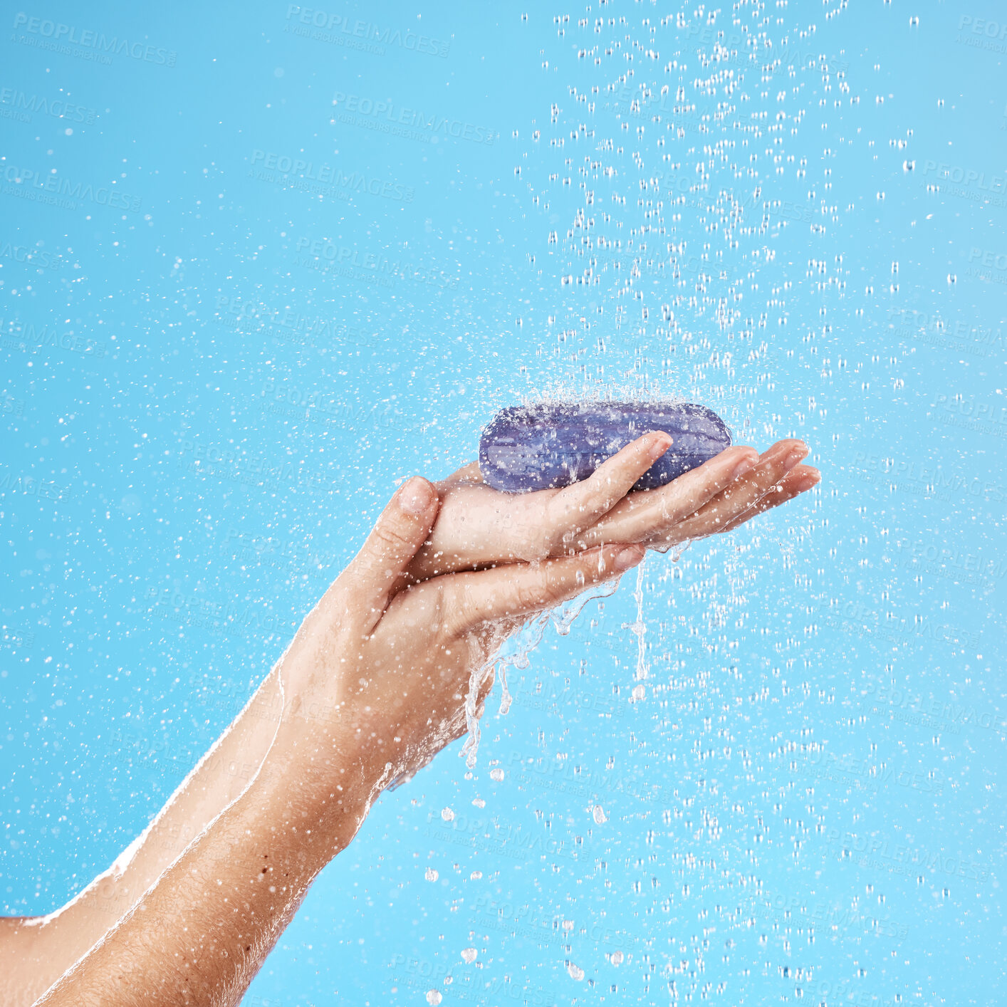 Buy stock photo Shower, soap and woman hands in a studio to wash her hands or body for hygiene, wellness or health. Water, clean and closeup of model holding soap bar for self care while isolated by blue background.