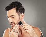 Shave, razor and man cut beard hair for grooming and hygiene or health and wellness on a grey studio background.  Epilation, shaving and beauty with electric razor and facial routine for male 