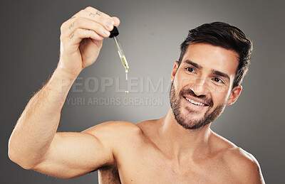 Buy stock photo Skincare, serum and beauty with a man model in studio on a gray background for wellness or antiaging. Product, oil and face with a handsome young male posing to promote natural or organic treatment