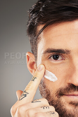 Buy stock photo Man, face and cream for beauty, skincare and wellness with hand against a grey studio background with mockup. Male model with facial lotion on sunscreen lotion for skin health and protection from uv