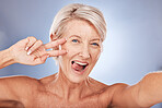 Beauty, peace sign selfie and mature woman for skincare, health and wellness with silly and goofy expression on a studio background. Anti aging, hand gesture and senior female for skin care 