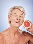 Grapefruit, skincare and senior woman with food for beauty, aging and wellness against a grey studio background. Smile, healthy and excited elderly model with a fruit with nutrition for body