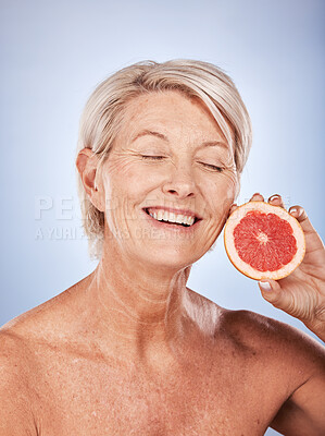 Buy stock photo Grapefruit, skincare and senior woman with food for beauty, aging and wellness against a grey studio background. Smile, healthy and excited elderly model with a fruit with nutrition for body