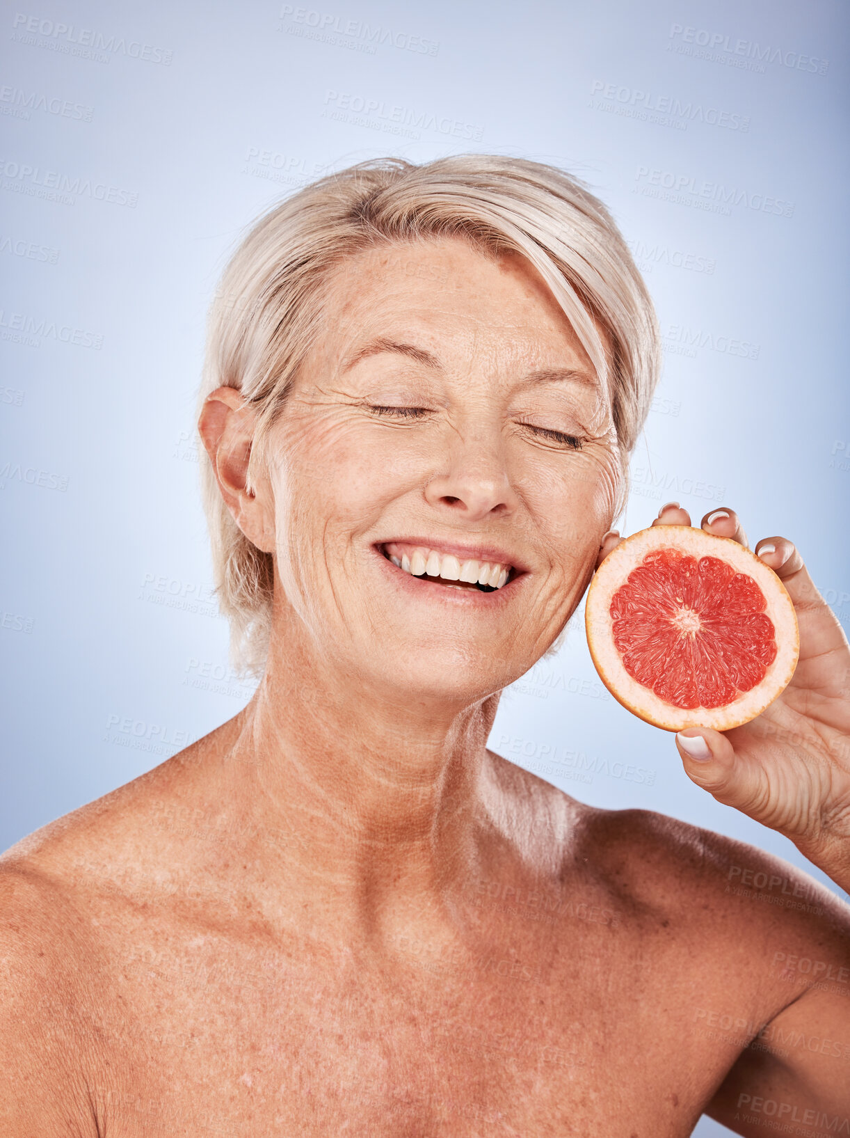 Buy stock photo Grapefruit, skincare and senior woman with food for beauty, aging and wellness against a grey studio background. Smile, healthy and excited elderly model with a fruit with nutrition for body