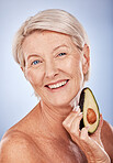 Skincare, beauty and senior woman with avocado for health, wellness and diet against a grey studio background. Fruit, smile and face portrait of an elderly person with food for nutrition and body