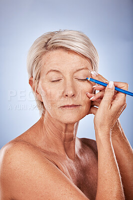 Buy stock photo Eyeliner, makeup and senior woman with beauty against a grey studio background. Cosmetic, color and elderly model with focus while applying cosmetics to face and eyelid with pencil during retirement