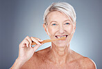 Mature woman, toothbrush and portrait for health, wellness and oral care on a grey studio background. Brushing teeth, clean and senior female cleaning her mouth for oral care or dental hygiene 