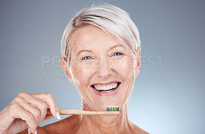Portrait, senior woman and brushing teeth for dental hygiene, fresh breath and smile against grey studio background. Oral health, mature female and elderly lady with toothbrush and cleaning mouth.