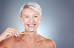 Smile, dental and senior woman brushing teeth for healthcare, wellness and breath against a grey mockup studio background. Happy, healthy and portrait of an elderly model with toothpaste for breath