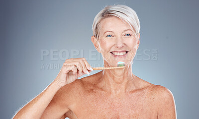 Buy stock photo Teeth, dental care and mature woman brushing teeth with toothbrush and toothpaste on gray background with smile on face. Morning routine, healthcare and fresh, happy senior lady in studio portrait.