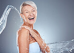 Water splash, health and portrait of senior woman laughing and happy on gray background with mockup space. Skincare, wellness and beauty, mature lady splashed with water with smile on face in studio.