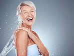 Beauty, senior and cleaning body with water splash for skincare, washing and hygiene routine. Happy, health and natural body care of mature woman model with gray studio advertising mockup.

