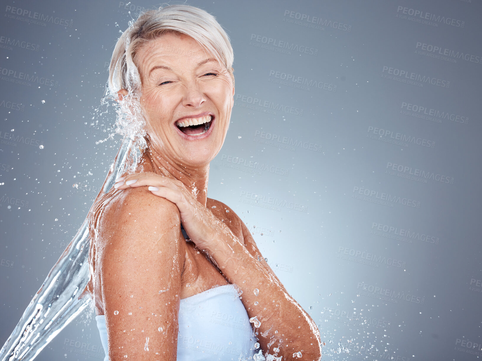 Buy stock photo Beauty, senior and cleaning body with water splash for skincare, washing and hygiene routine. Happy, health and natural body care of mature woman model with gray studio advertising mockup.

