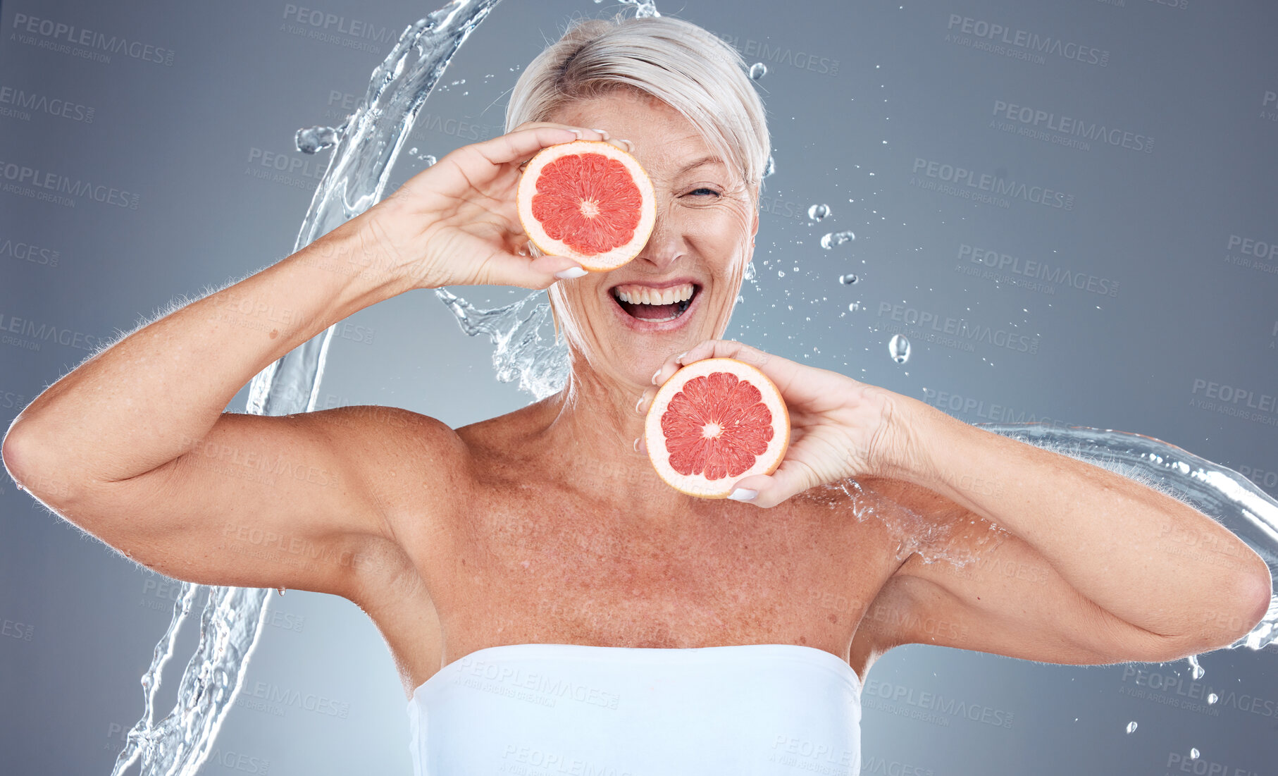 Buy stock photo Grapefruit, water and senior woman with a splash for skincare, beauty and wellness against a grey studio background. Water splash, health and excited elderly model with fruit for diet lifestyle