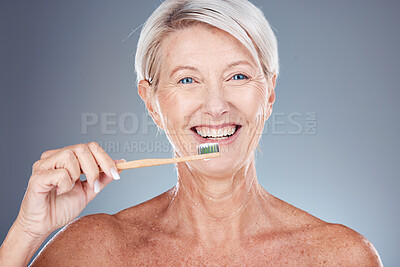 Buy stock photo Dental, studio and senior woman brushing teeth on a gray background. Oral health, wellness and routine of elderly female from Canada holding toothbrush and cleaning teeth for hygiene and oral care

