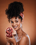 Face, beauty and pomegranate with a black woman model in studio on a brown background for natural vitamins. Skincare, wellness and luxury with an attractive young female posing to promote nutrition