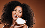 Hair, model and beauty portrait with coconut for natural curly hair care cosmetic treatment. Healthy, beauty and black woman holding tropical and wellness fruit on brown studio background.
