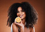 Orange, health and face of a black woman with fruit for skincare, nutrition and marketing against a brown studio background. Advertising, vitamin c and African model with food for nutrition and detox
