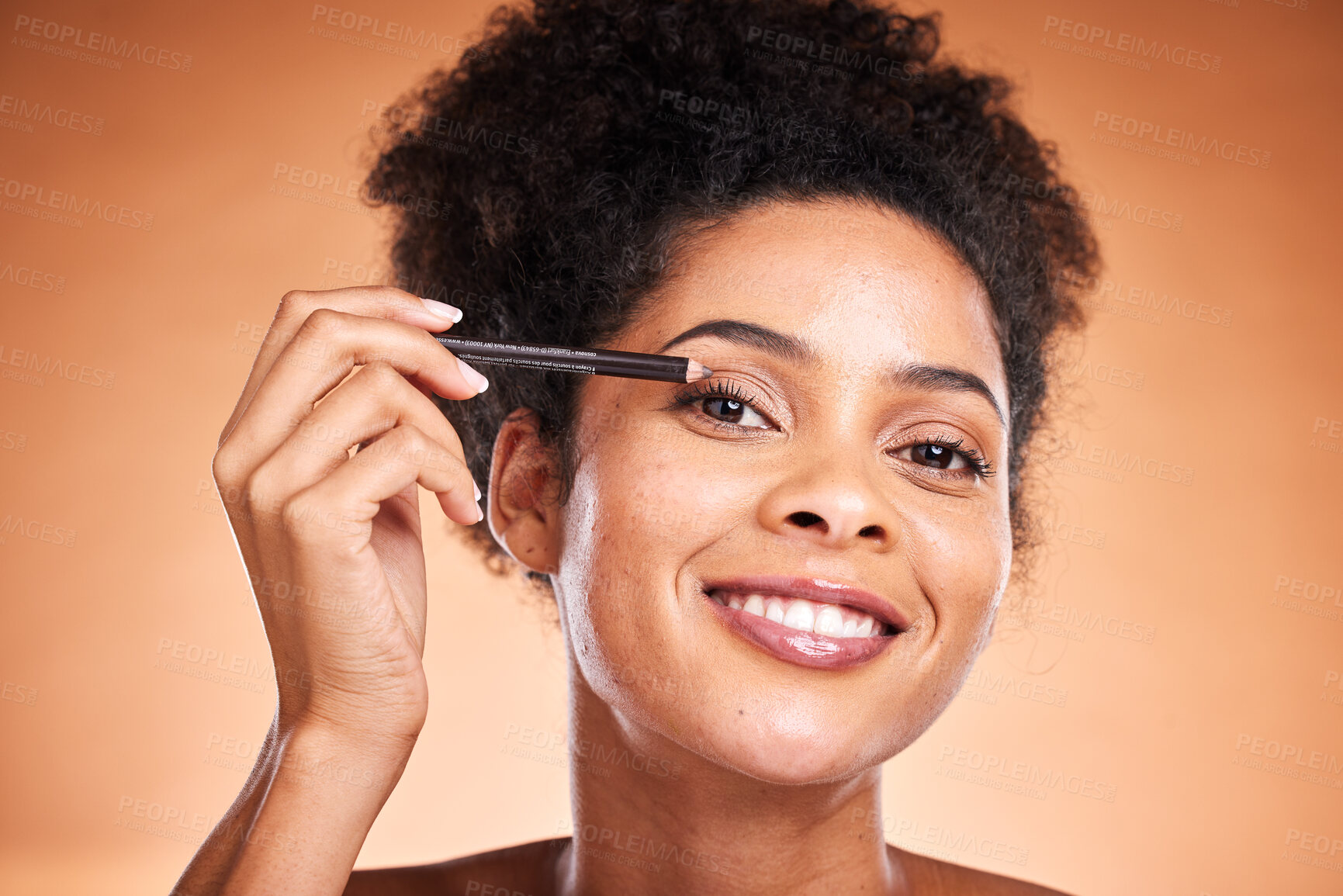 Buy stock photo Eyeliner, beauty and portrait of a black woman doing a cosmetic makeup routine in the studio. Cosmetics, beautiful and happy African model doing eye make up with pencil isolated by orange background.