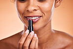 Makeup, lips and lipstick with a black woman model using cosmetics for her lip in studio on a beige background. Beauty, cosmetic and mouth with a female posing to promote a beautification product