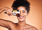 Beauty, makeup and portrait of black woman with brushes in studio isolated on an orange background. Self care, skincare and female model with cosmetics, products or makeup brushes for skin aesthetic.
