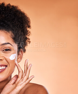 Buy stock photo Skincare, beauty and black woman with facial cream on orange background studio for wellness. Makeup, cosmetics and half face of girl apply lotion, sunscreen and skincare products for dermatology care