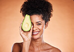 Beauty, skincare and avocado with a model black woman in studio on a beige background for wellness or antioxidants. Portrait, skin or nutrition with an attractive young female proud of healthy eating