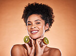 Kiwi fruit, beauty and black woman healthcare or vitamin c nutrition for skincare health. Portrait of African girl model, diet wellness or healthy cosmetics and facial care in brown background studio