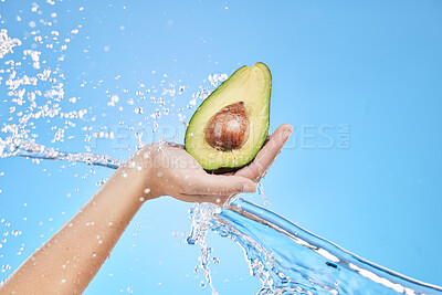 Buy stock photo Hand, water and avocado for beauty splash and organic skincare product on a blue studio background. Avo, vegetable and natural produce for bodycare, skin care and nutrition or healthy diet