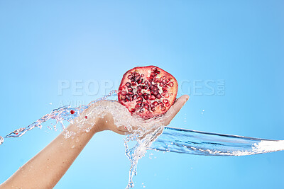 Buy stock photo Water splash, hand and pomegranate for health in studio on blue background mockup. Fresh fruits, cleaning hygiene and female model holding fruit food for vitamin c, organic cosmetics or glowing skin.