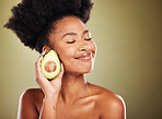 Face, skincare and black woman with avocado for health, wellness and nutrition on green background. Eyes closed, healthy food and antioxidant diet of happy female model from Nigeria with glowing skin