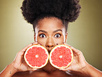 Face portrait, skincare and black woman with grapefruit isolated on a green studio background. Surprise, wow and female model holding healthy fruit for natural vitamin c, facial care or skin wellness