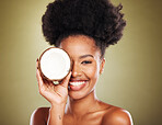 Black woman, fruit and skincare beauty for cosmetics, moisturizer or nutrition against a studio background. Portrait of African American female holding coconut with smile for healthy facial treatment