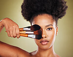 Black woman, makeup brush and beauty in studio for skincare portrait, wellness and cosmetics by backdrop. African woman, model and face with cosmetic tools, hand and powder for skin by background