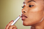 Lipstick, black woman and skincare for wellness, cosmetics, smooth lips or against brown studio background. Makeup, African American female or girl with lip balm, for gloss or soft for natural beauty