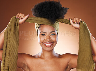 Buy stock photo Face, beauty and black woman with hair scarf in studio on brown background. Fashion, hair care and happy female model tying her afro hair with fabric head wrap for unique hair style and healthy hair.