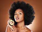 Avocado, black woman and skincare beauty for cosmetics, moisturizer or nutrition in brown studio background. Portrait of African American female holding fruit with diet for healthy facial treatment
