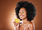 Orange, black woman and vitamin c beauty, skincare and wellness, healthy food or detox diet, natural cosmetics and afro on studio background. Happy young vegan model eating citrus fruit for nutrition