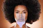 Beauty, hair care and black woman with an afro comb in a studio isolated by a brown background. Health, wellness and portrait of a African model with big beautiful natural curly hair and a brush.