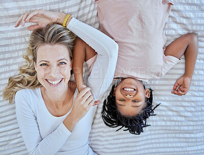 Buy stock photo Top view, family and mother with foster girl on bed, relaxing and bonding. Love, care and adoption portrait of happy mom with black kid in bedroom, smiling and enjoying quality time together in house
