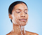 Woman, shower and water splash on face for skincare hydration or clean hygiene against blue studio background. Female in facial wash with water to hydrate or cleanse for hygienic body care treatment