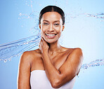 Portrait, skincare and water splash of woman in studio on a blue background. Hygiene body care, cleaning and female model from India showering, bathing or washing skin for health, wellness and beauty