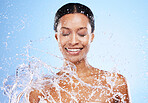 Water splash, shower and washing with a black woman in studio on a blue background for hygiene or hydration. Bathroom, happy and cleanliness with a young female model washing his skin for fresh care