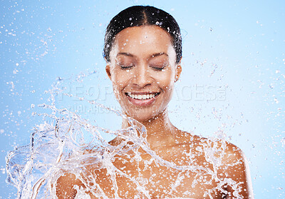 Buy stock photo Water splash, shower and washing with a black woman in studio on a blue background for hygiene or hydration. Bathroom, happy and cleanliness with a young female model washing his skin for fresh care